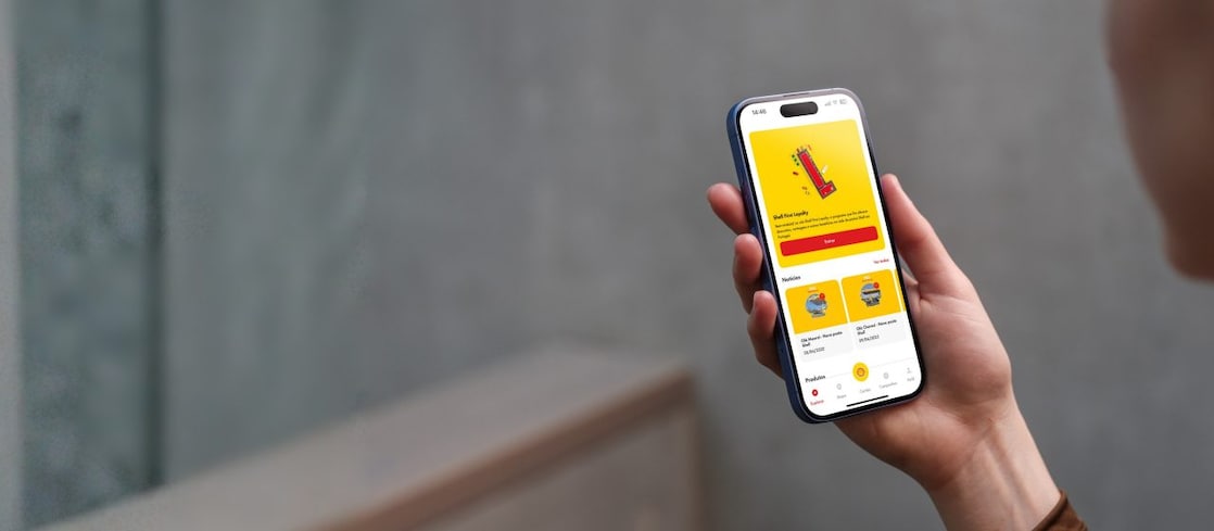 Cliente a segurar um smartphone com a app Shell First Loyalty aberta.