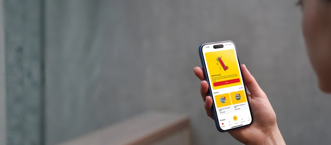 Cliente a segurar um smartphone com a app Shell First Loyalty aberta.