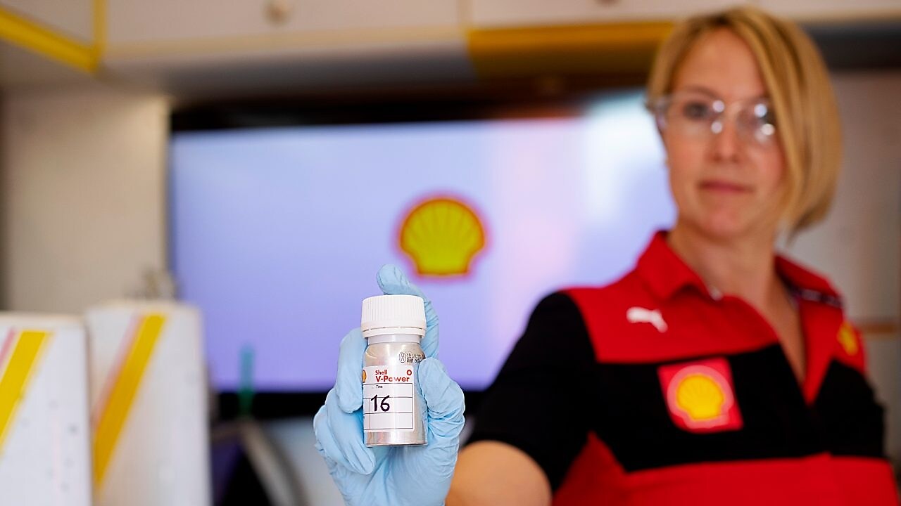 Mãos a segurar tubo de Shell V-Power em laboratório